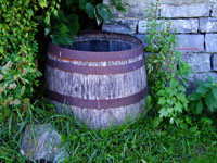 old rain barrel against stone wall