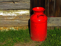 red milk can against barn wall